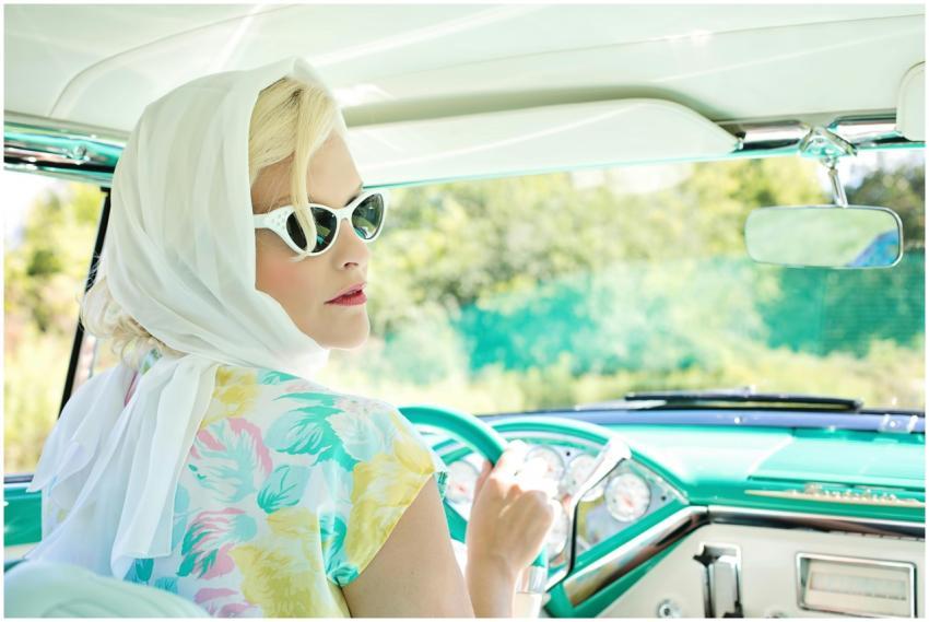 Elegant woman in vintage attire driving a classic