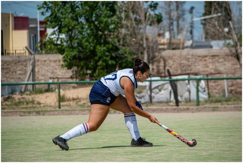 A female athlete practicing field hockey on an out