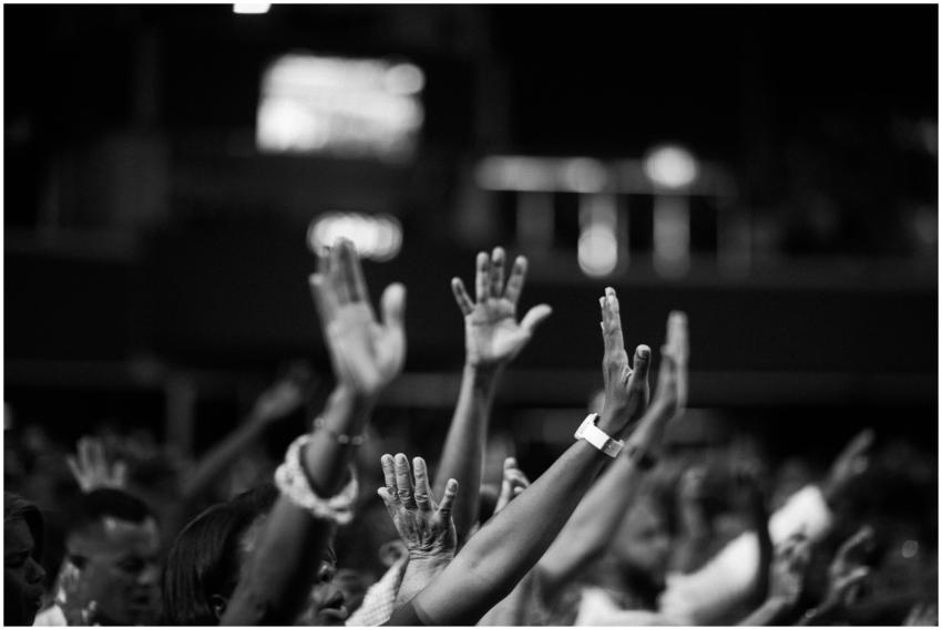 A group of people raising hands in a black and whi