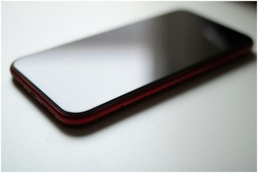 Close-up image of a red smartphone lying on a whit