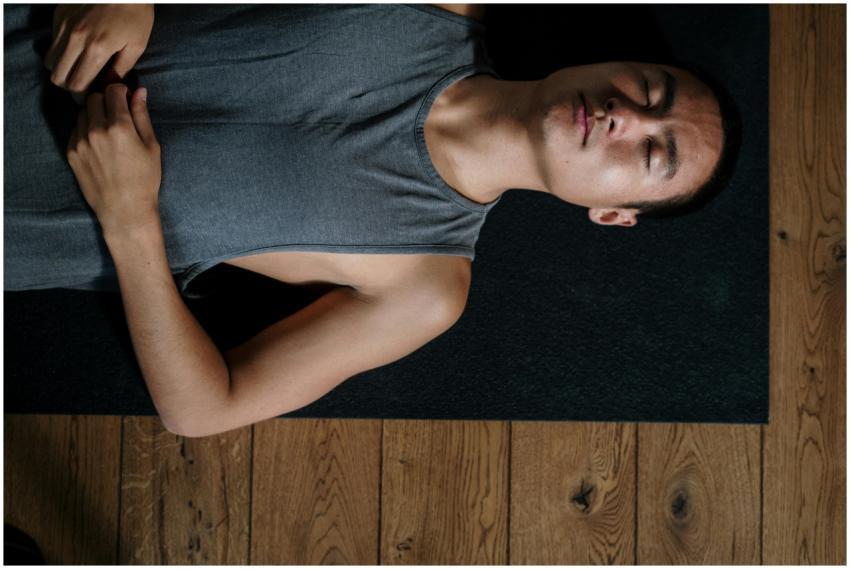 A man lies on his back in a yoga studio, relaxing
