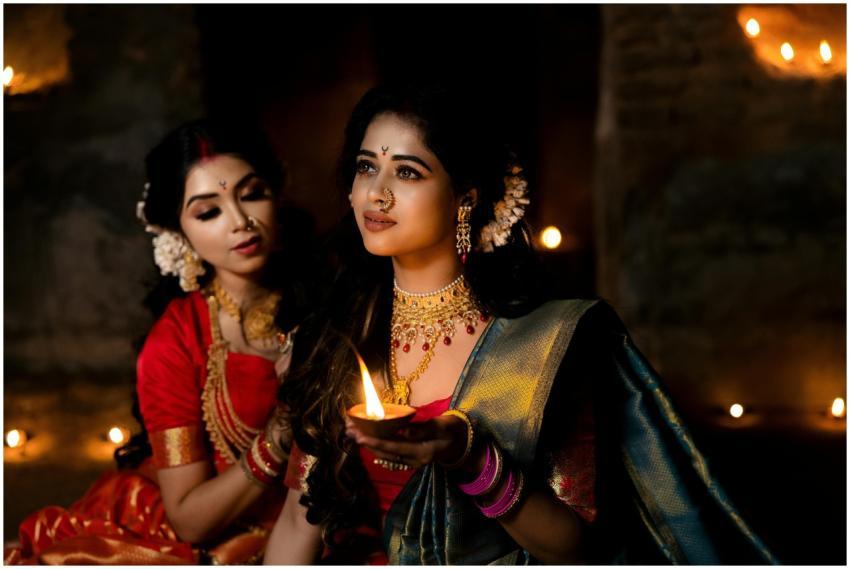 Two Indian women in sarees holding a diya, capturi