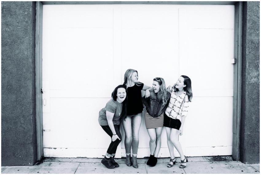 Four young women laughing together in front of an