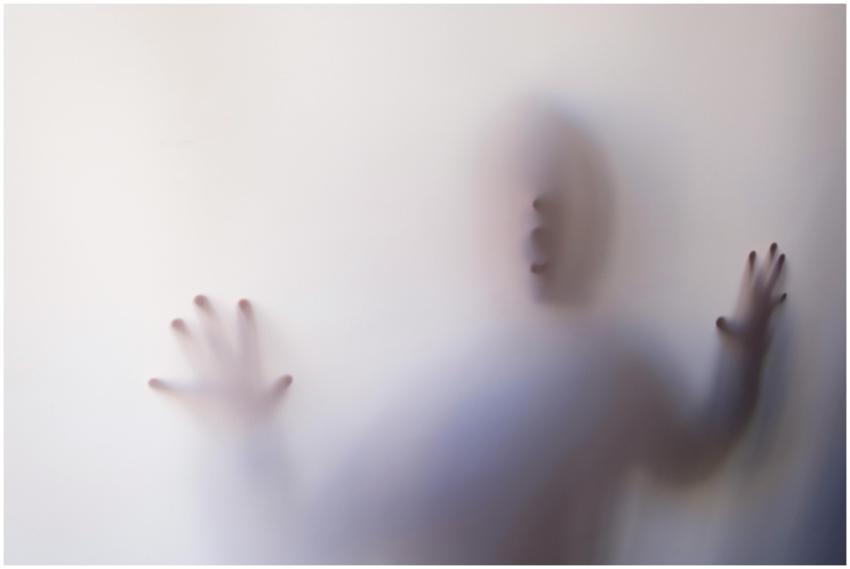 Eerie silhouette of a person pressing against a wh