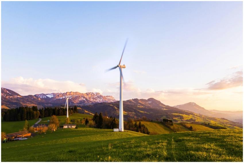 A wind turbine stands tall against a mountainous b