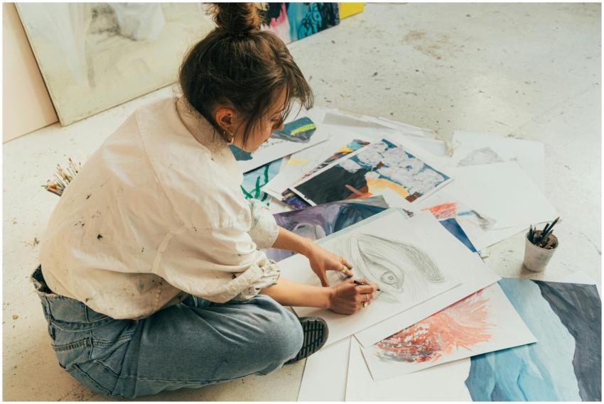 A young woman sketching on the floor surrounded by