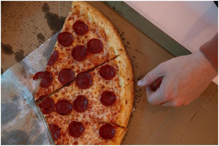 Hand reaching for a delicious pepperoni pizza slic