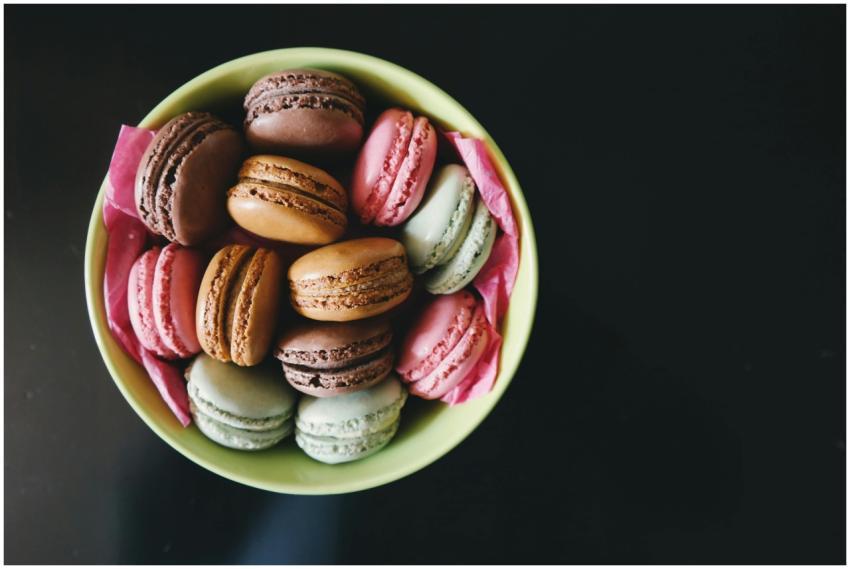 A vibrant assortment of macarons in a green bowl,