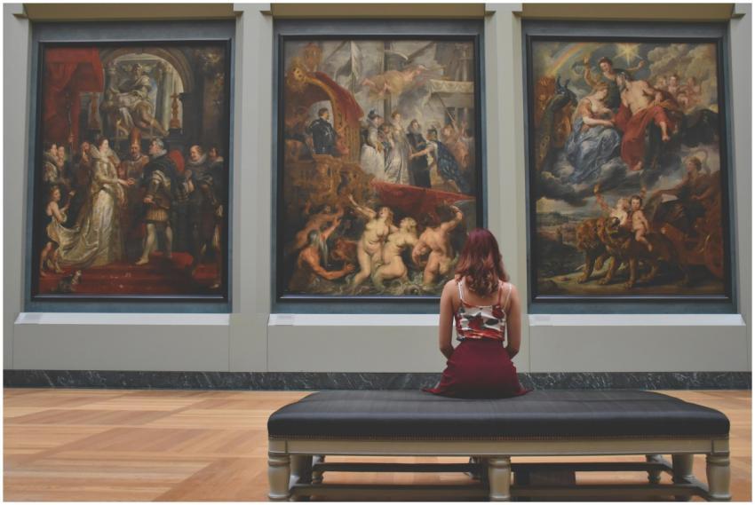 A woman observes classic paintings in an elegant m