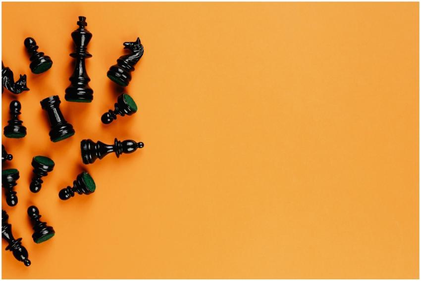 Scattered black chess pieces on an orange backgrou