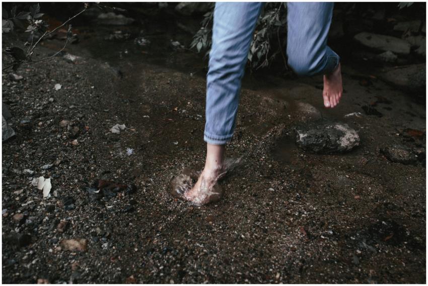 A person wearing blue jeans jumps barefoot in a ro