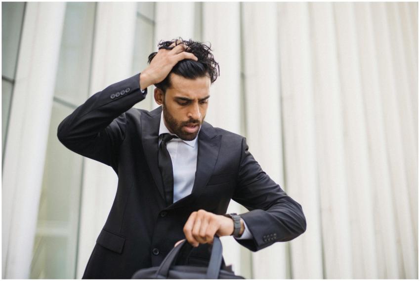 A businessman in a suit checks his watch, expressi