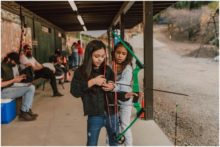 Two young girls practicing archery at an outdoor r