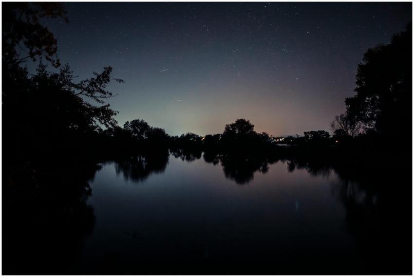 Peaceful lakeside view with starry night sky refle