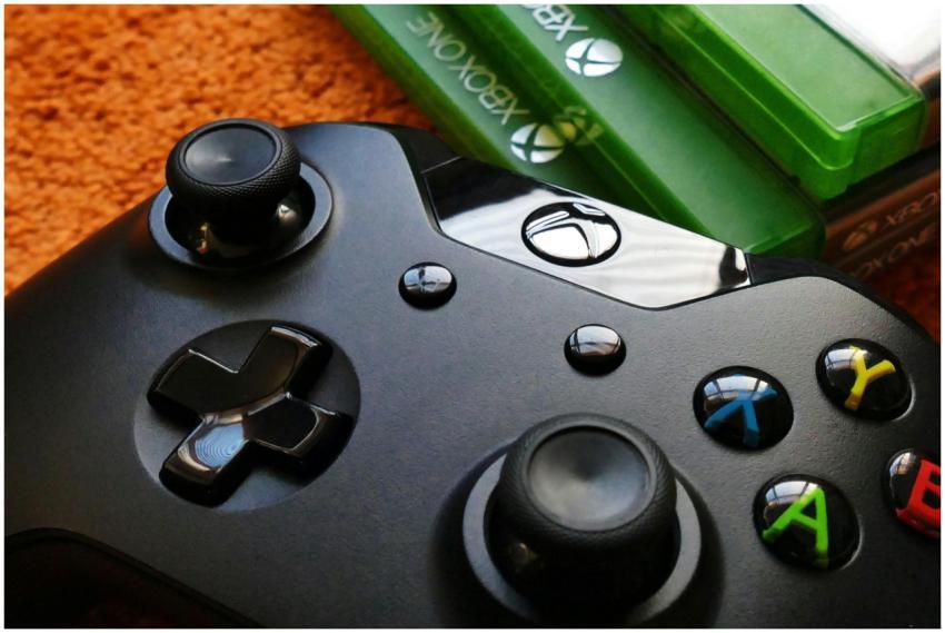 Xbox controller close-up with game cases on orange