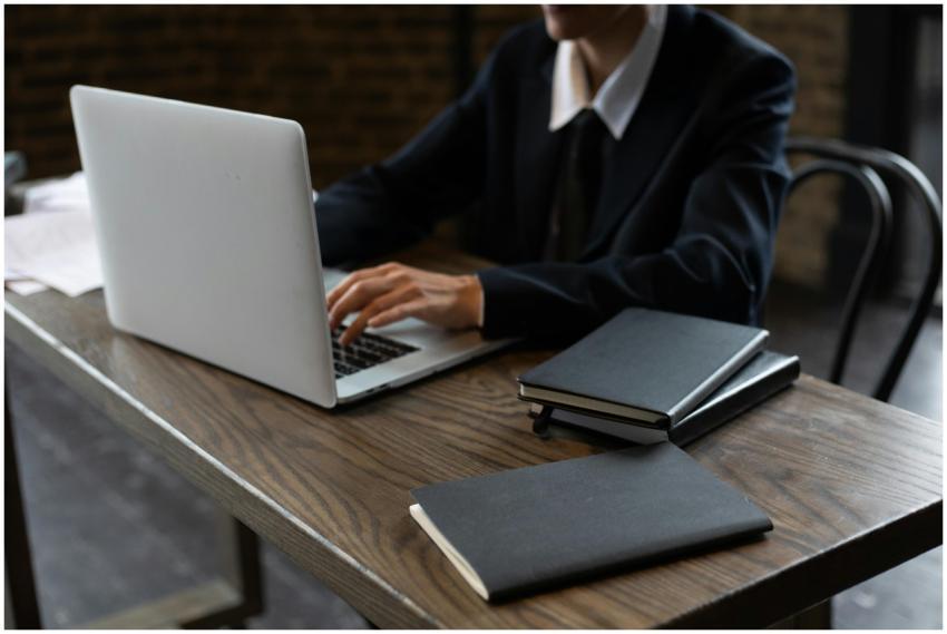 Close-up of a person in a suit typing on a laptop