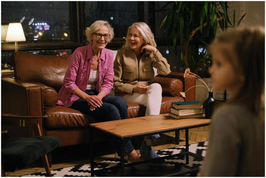 Two smiling senior women sitting on a sofa, engagi