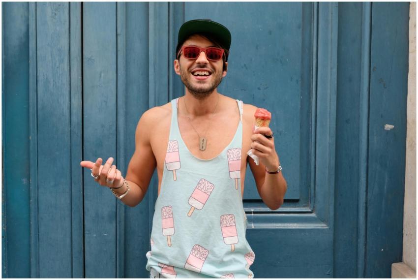 Happy man in Paris enjoying ice cream against a bl