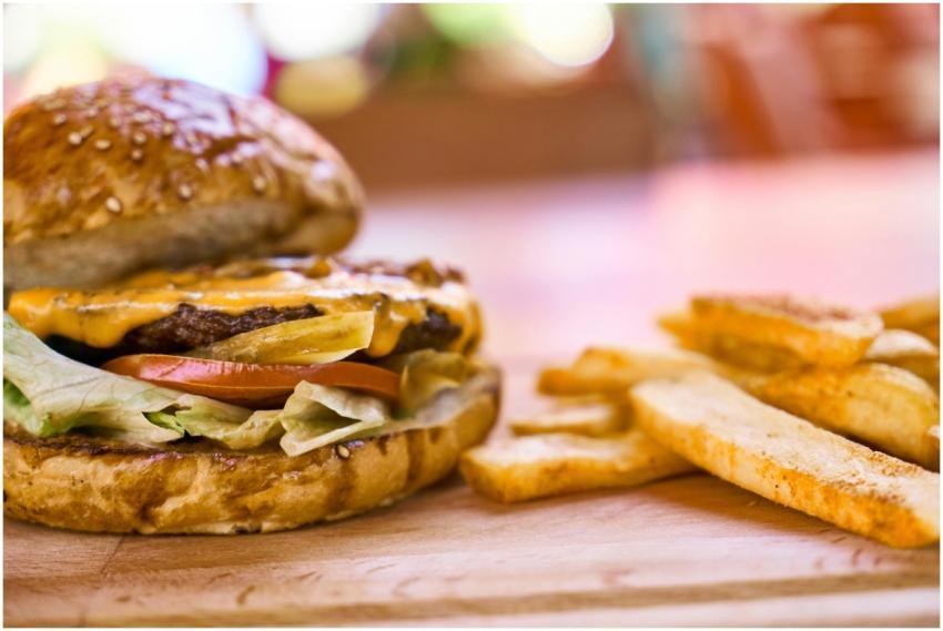 Close-up of a cheeseburger with fries on a wooden