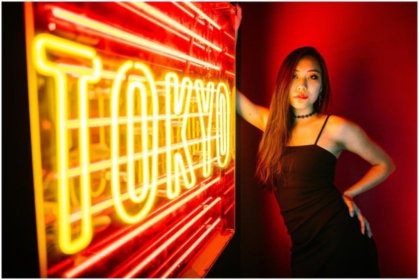 A stylish woman poses by a vibrant Tokyo neon sign