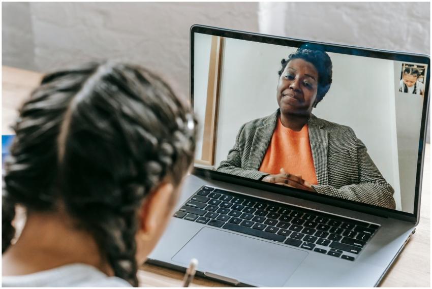 Child using laptop for online learning with teache