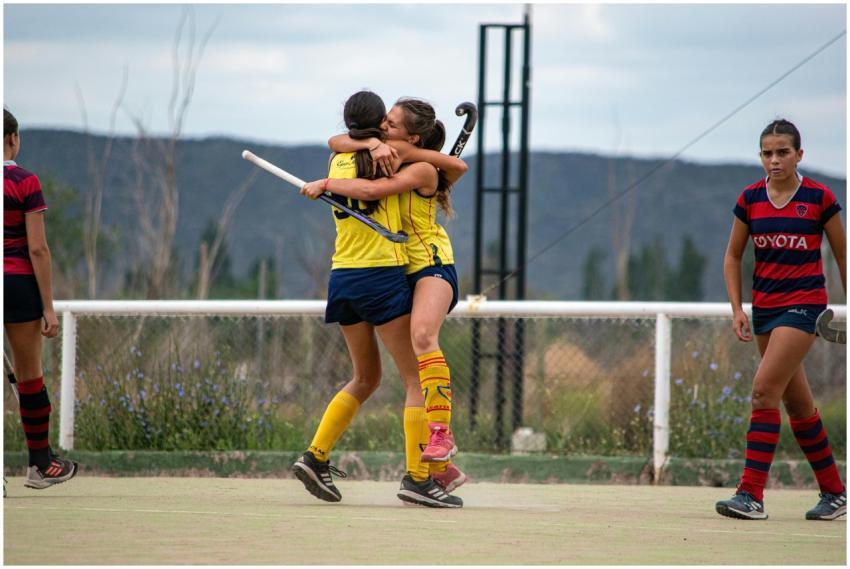 Two young female field hockey players celebrate on