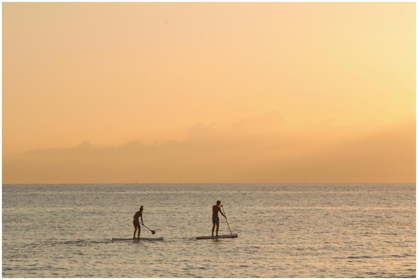 Two people paddleboarding at sunset in the tranqui