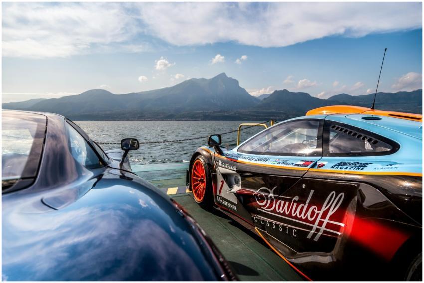 Supercars by a lake with a mountain backdrop, high