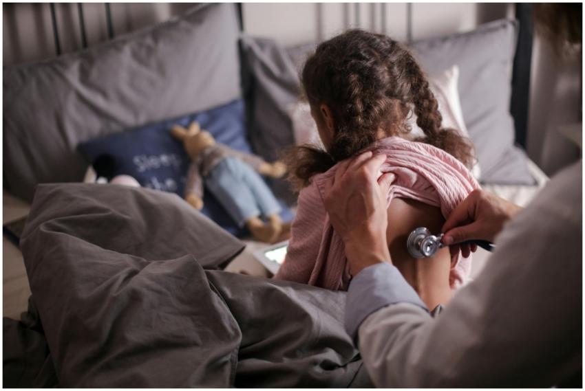 A pediatric doctor checks a child's back with a st