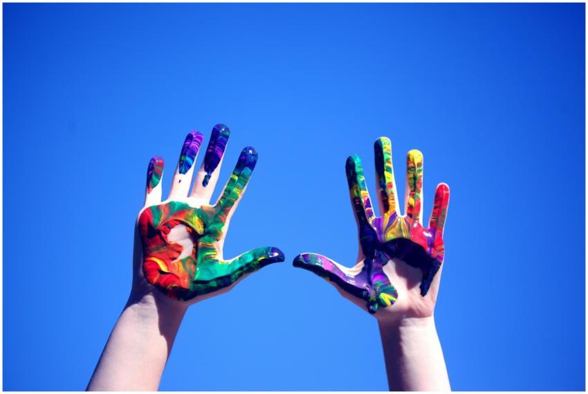 Colorful painted hands raised against a clear blue
