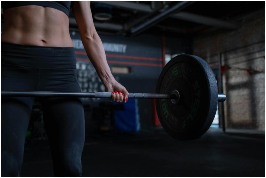 A fit woman lifting a barbell indoors highlights s