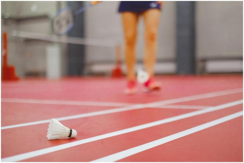 Focused badminton shuttlecock on red indoor court