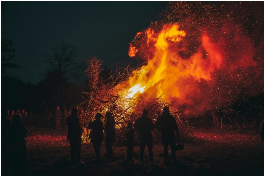 A blazing bonfire illuminates the night with silho