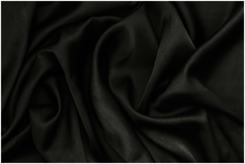 A close-up of smooth black fabric with rippling te