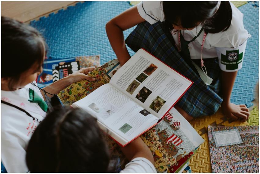 Three children actively reading books together in