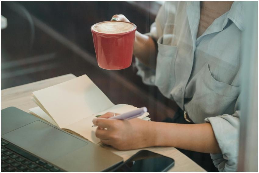 A woman writes in a notebook while enjoying a coff