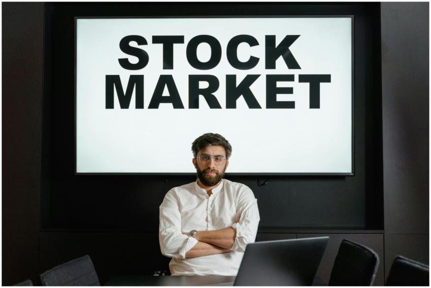 Confident businessman sitting in front of a stock