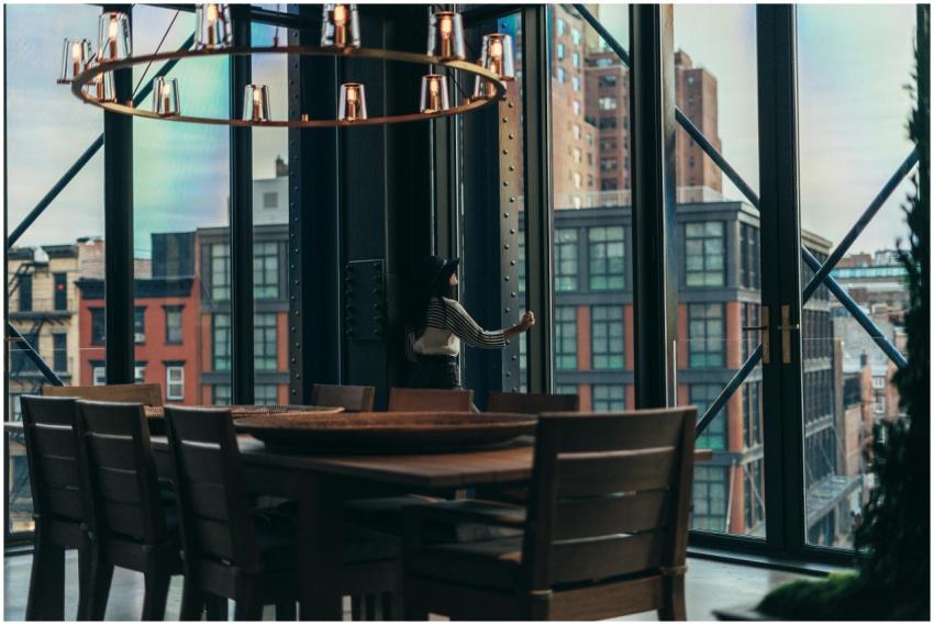 A woman stands by glass windows in a stylish inter
