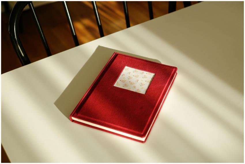 A red notebook with floral sticker on a sunlit tab