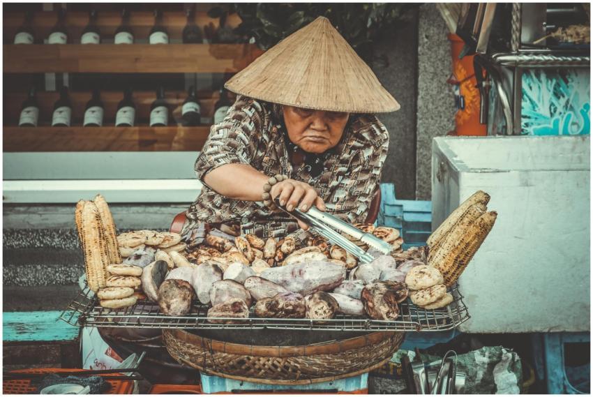 Asian woman grilling corn and sweet potatoes on a