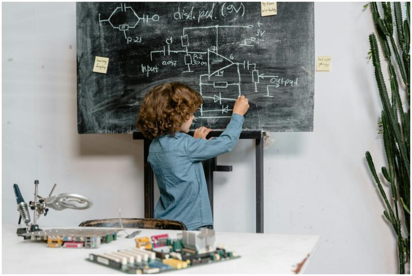 A young boy creatively draws a circuit diagram on