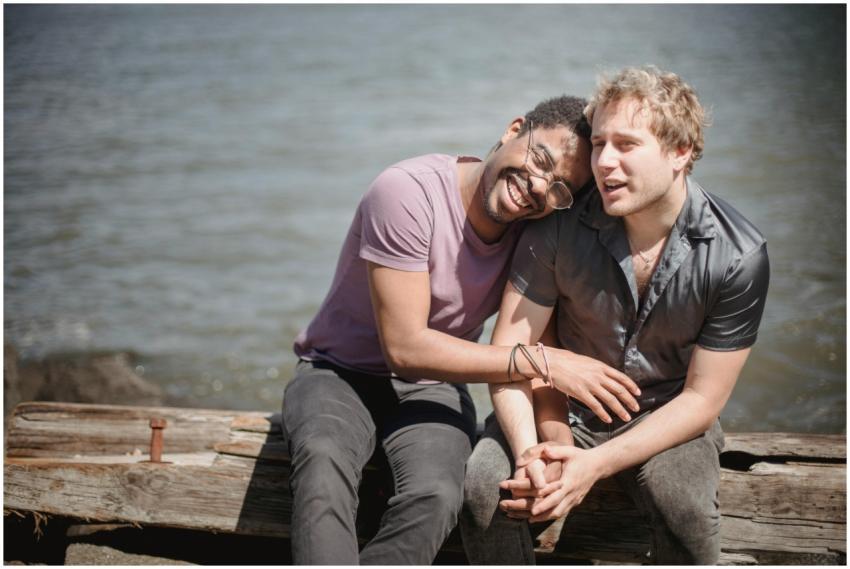Happy interracial gay couple sitting outdoors by t
