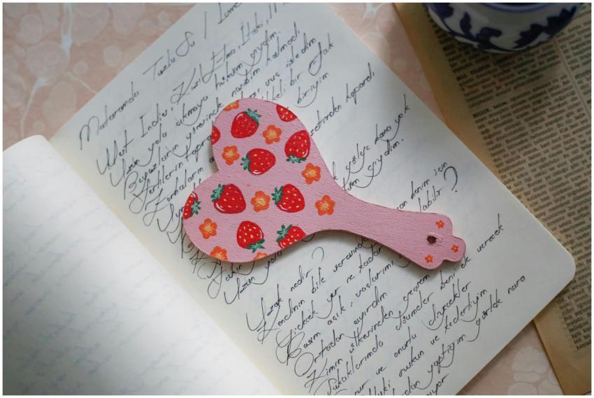 A strawberry-patterned pink paddle rests on open h