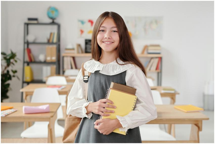 A cheerful teenage girl standing in a classroom ho