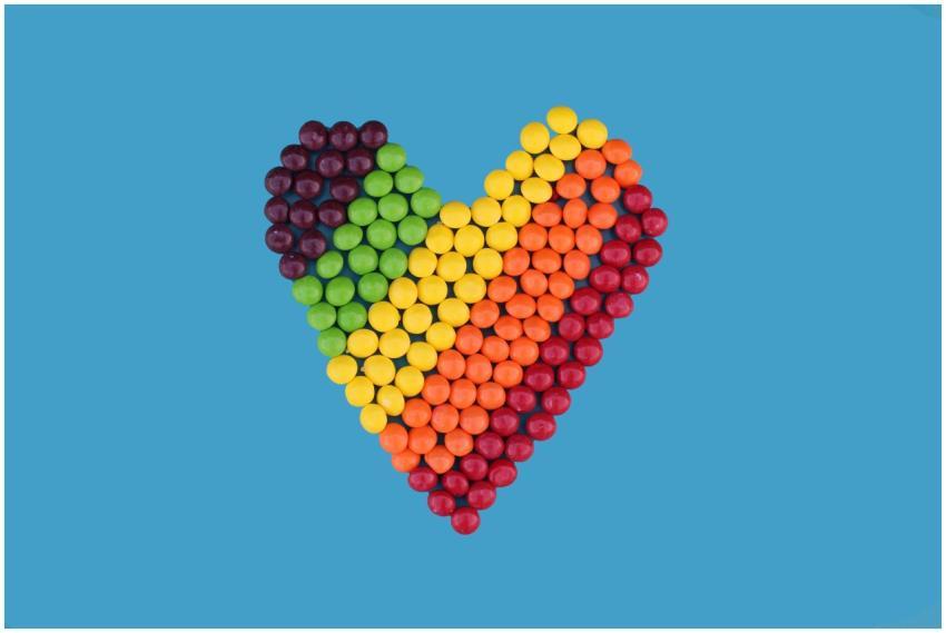 Rainbow-colored candies arranged in a heart shape