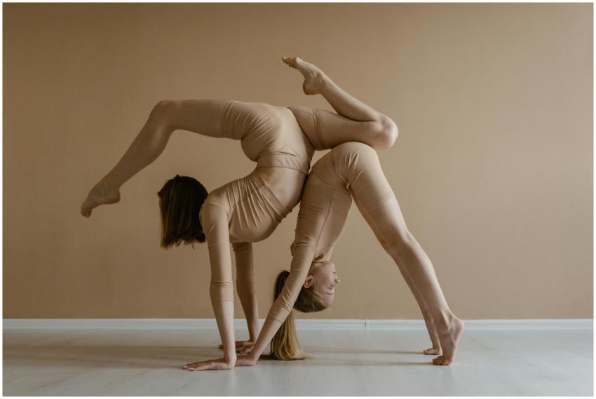 Two women perform a contortion pose, showcasing fl