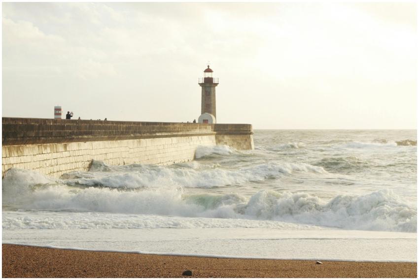 Lighthouse on Douro River breakwater with waves cr