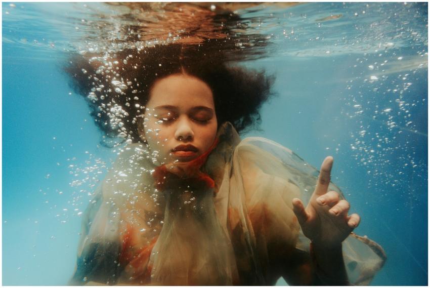 A serene underwater portrait of a woman with curly