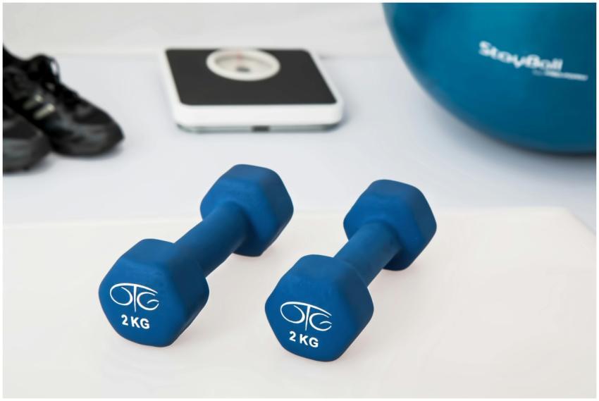 Blue dumbbells placed on a white surface with fitn