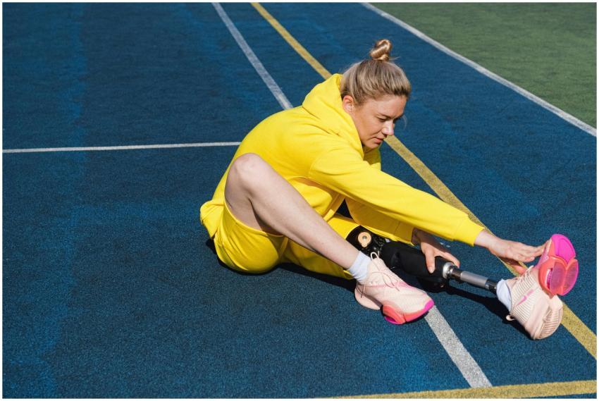 Woman in yellow sportswear stretches on track with